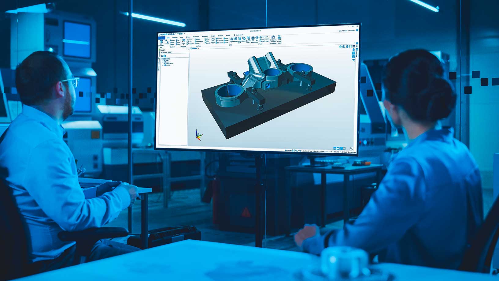 Dos ingenieros en un entorno de fabricación observando un modelo CAD 3D en una pantalla grande
