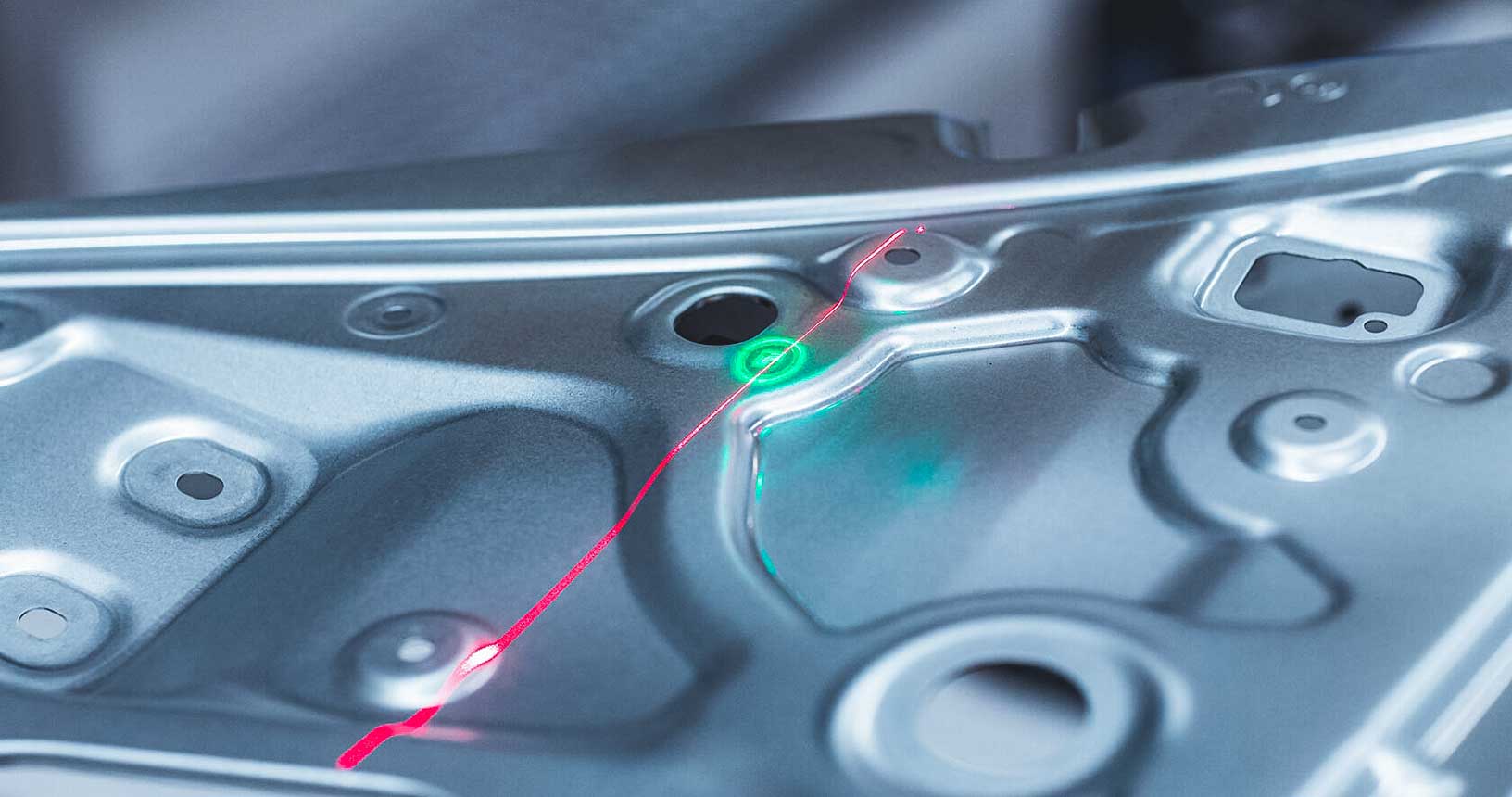 Vista ravvicinata di un pezzo di lamiera in fase di scansione con linea laser rossa in evidenza 