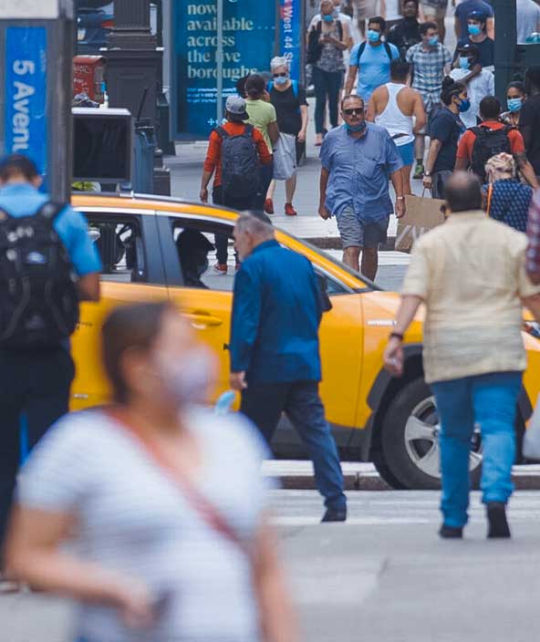 Menschengruppen mit Masken überqueren eine Straße in New York City