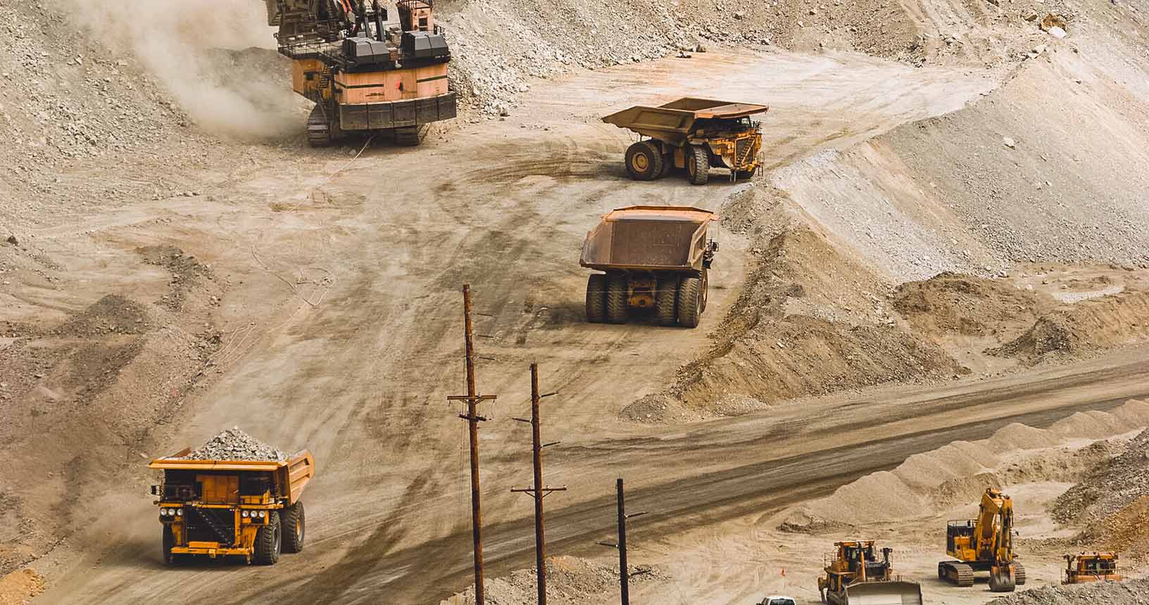 caminhões de transporte e escavadeiras em uma mina a céu aberto