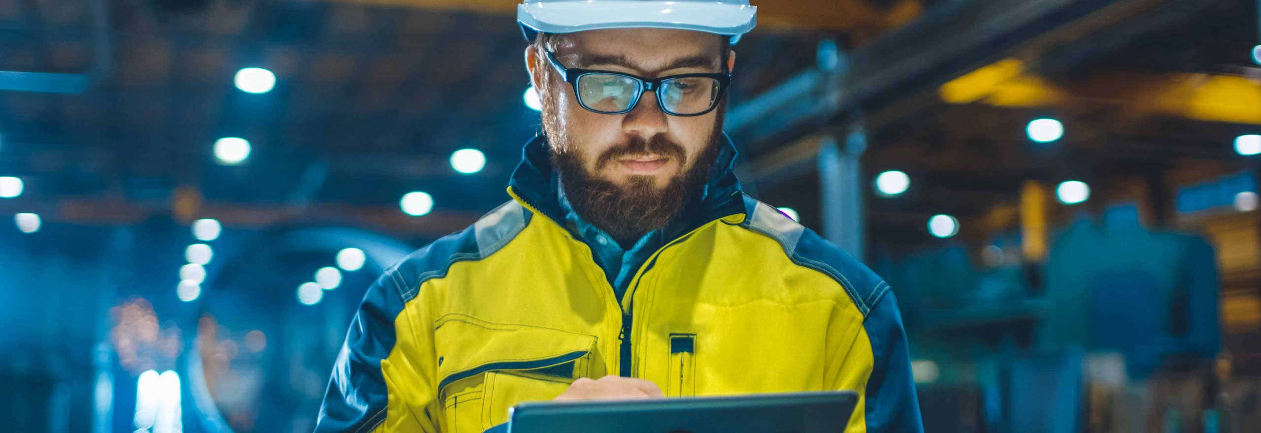 Industrial engineer in hardhat, wearing safety jacket using a touchscreen tablet computer.