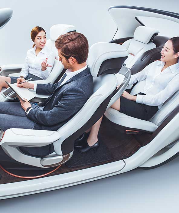 Três pessoas sentadas em um arranjo futurista de assentos automotivos