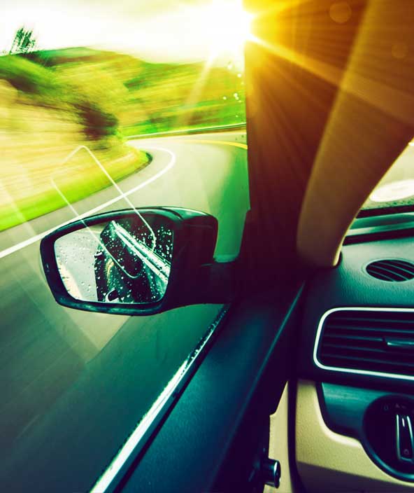 View from the inside of a car driving down a road with the wing mirror in view<em> </em>