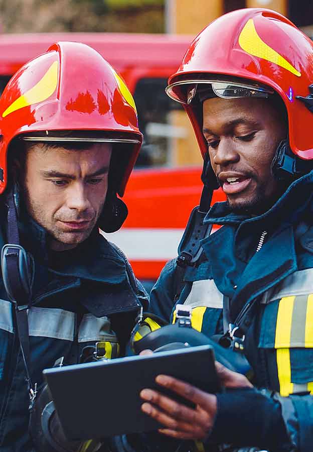 Due primi soccorritori completamente equipaggiati esaminano le informazioni su un iPad
