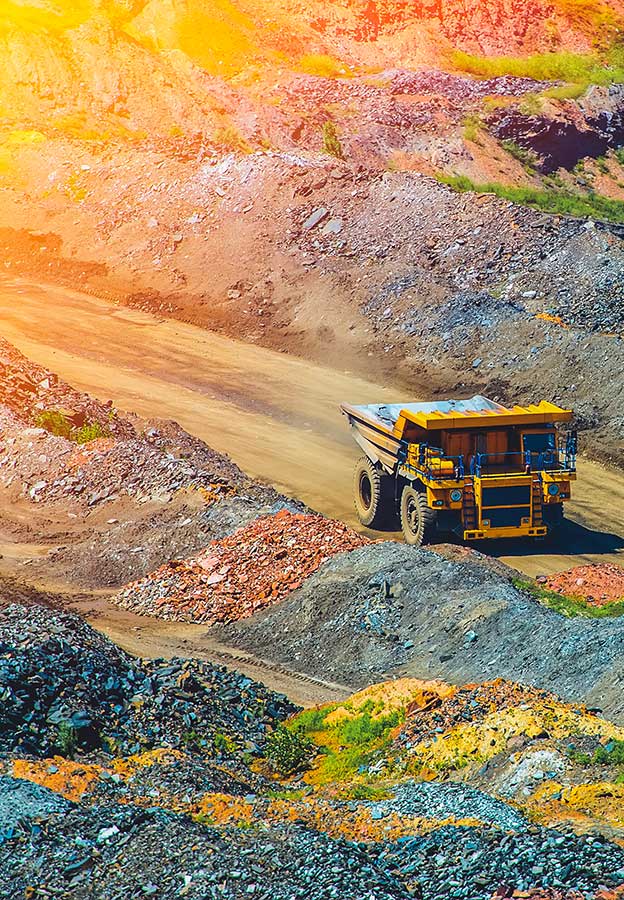Caminhões de transporte levando material por uma mina a céu aberto ao anoitecer