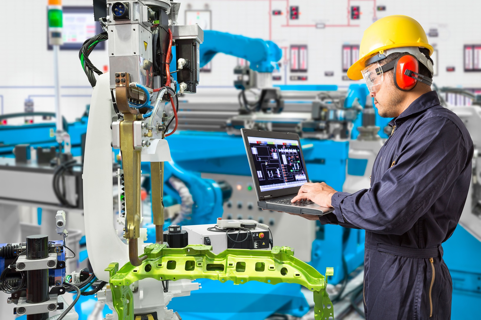 Engineer using laptop computer maintenance automatic robotic hand machine tool in automotive industry manufacturing factory