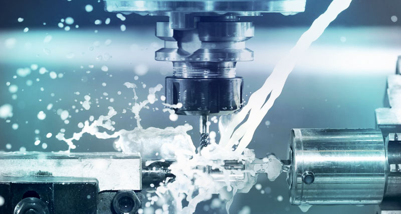 Image of a CNC machine in operation, cutting metal alongside flowing water, demonstrating CAD CAM efficiency.