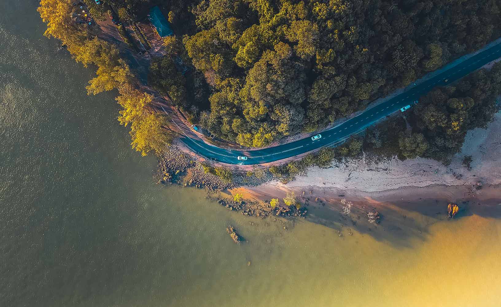 Uma vista aérea de um trecho de estrada sinuosa próximo a uma extensão de água