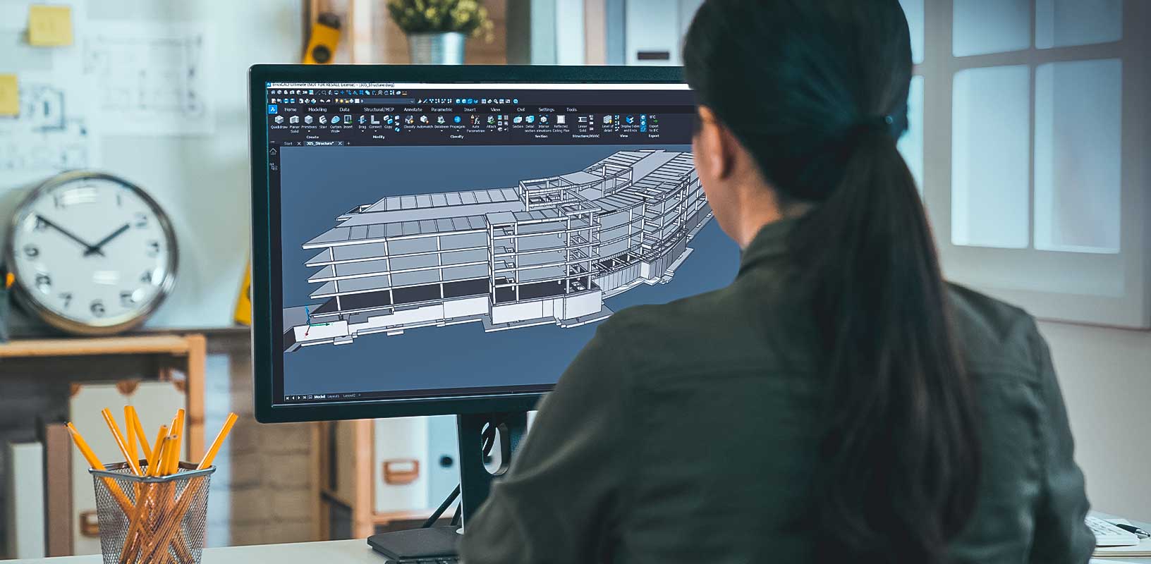 Back view portrait of woman engineer working on desktop computer with blueprints on screen in office. young female architect worker sitting in studio looking at pc screen interior design plan