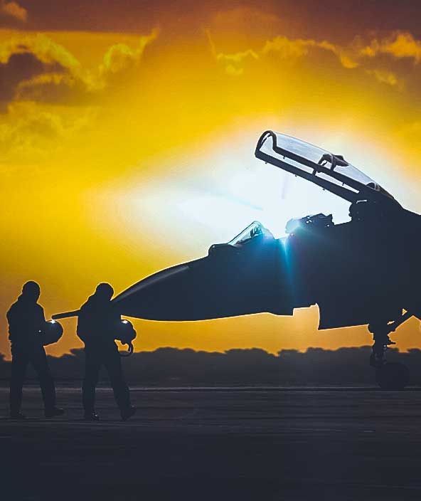 silhouette di un jet da combattimento parcheggiato con sullo sfondo il tramonto 