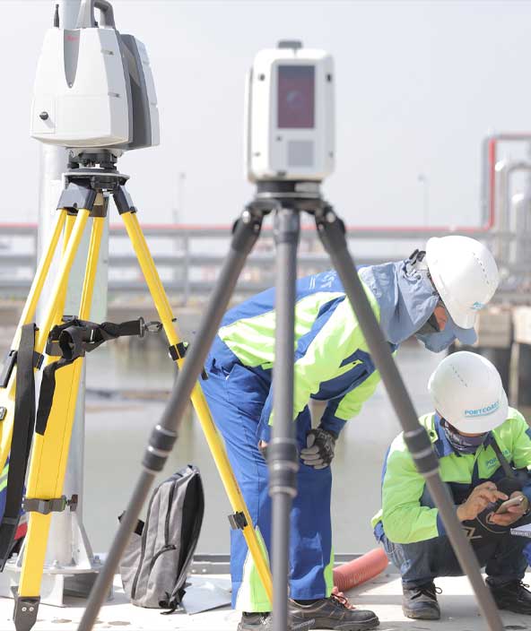 Un gruppo di operai edili e un'apparecchiatura di scansione laser nel cantiere di ricostruzione di un porto in Vietnam