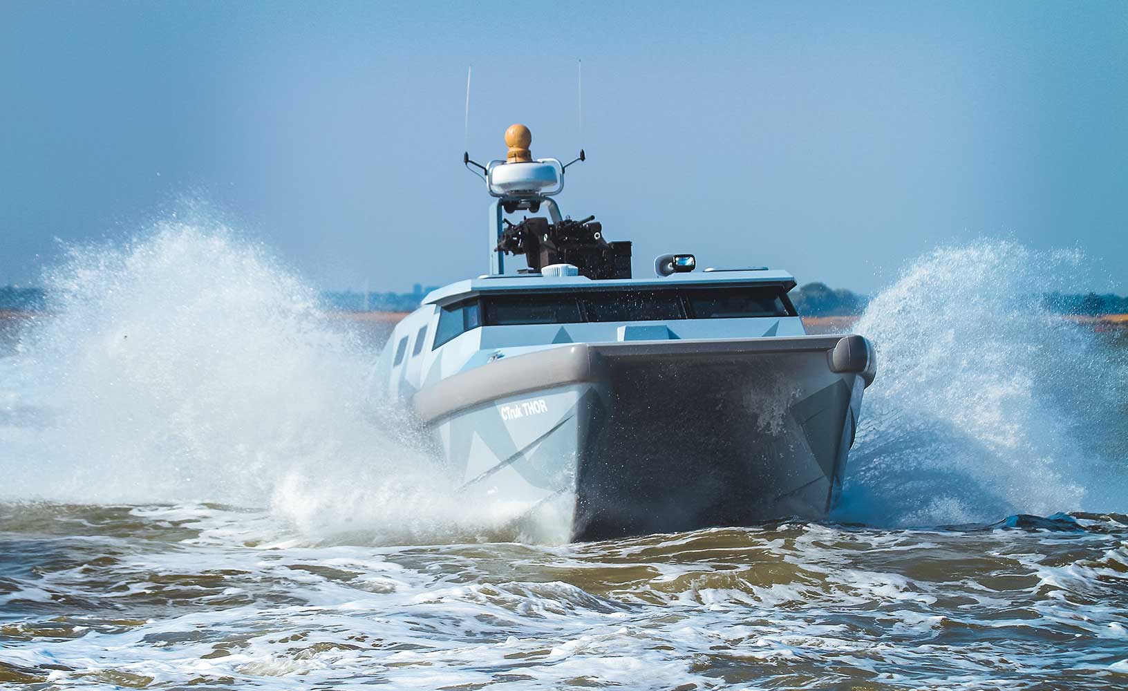 Ein küstennahes blau-graues Schiff auf dem Wasser, das durch einen GAJT-710MS vor Jamming geschützt wird.