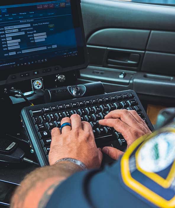 Police officer in vehicle uses software.