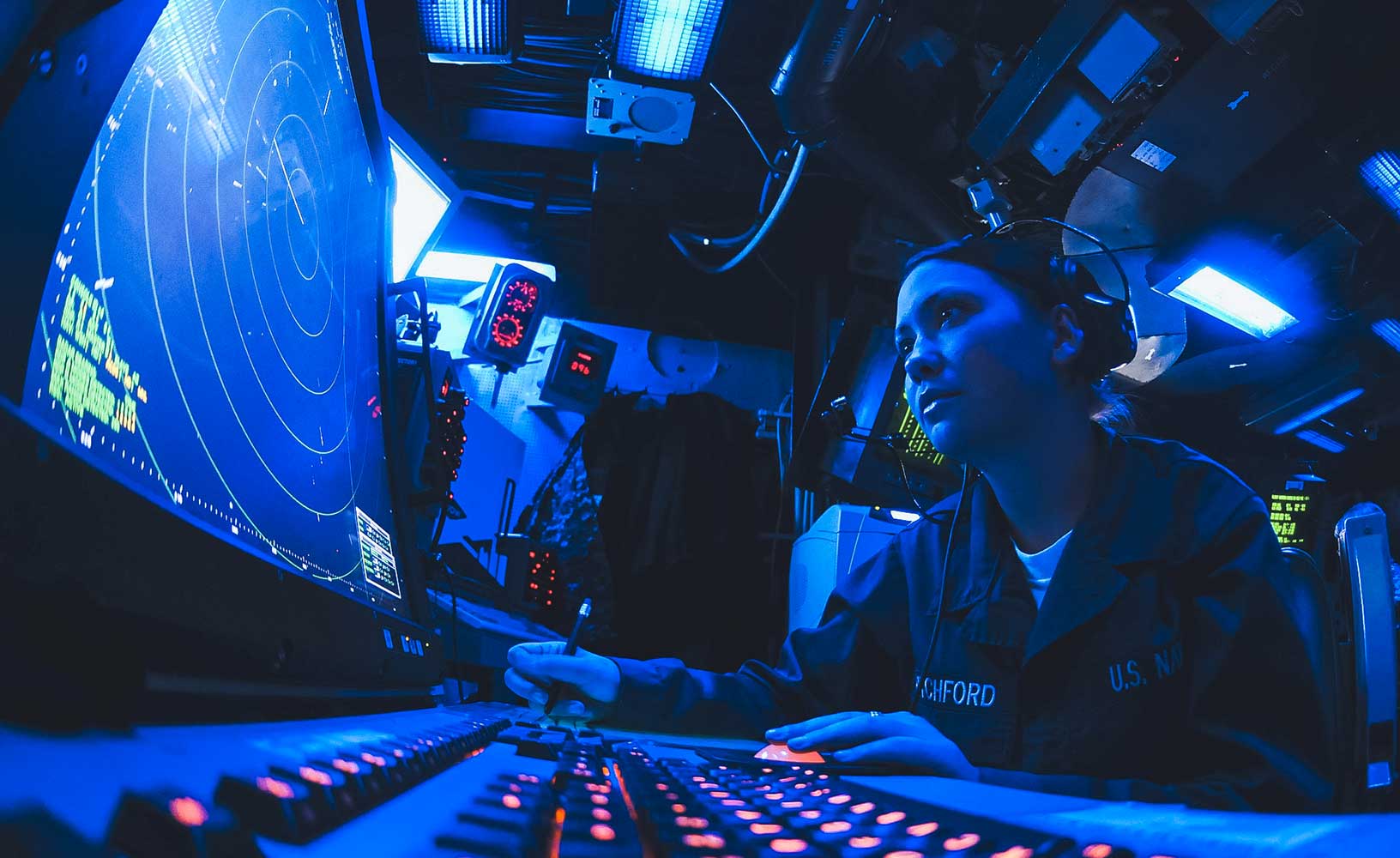Un tecnico radar della marina statunitense controlla i suoi schermi e prende appunti