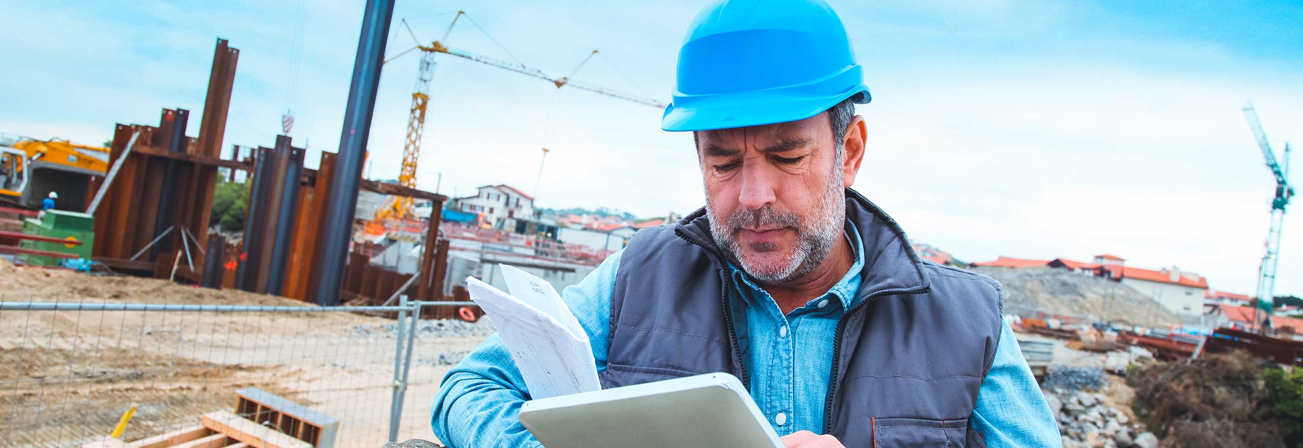 A man in hard hat reviews documents at jobsite
