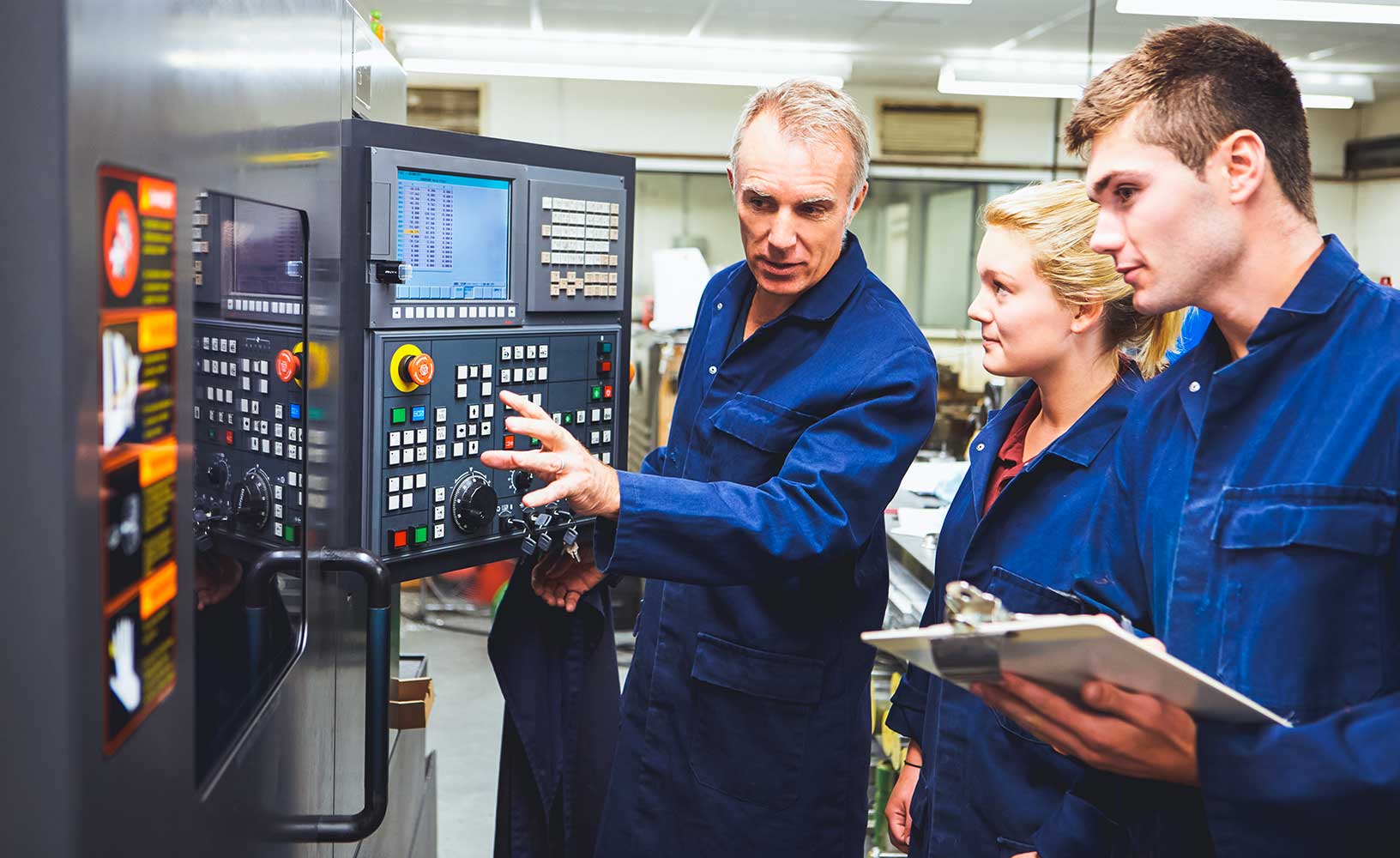A team of three manufacturing workers reviewing a machines data and functionality to review its' overall equipment effectiveness.