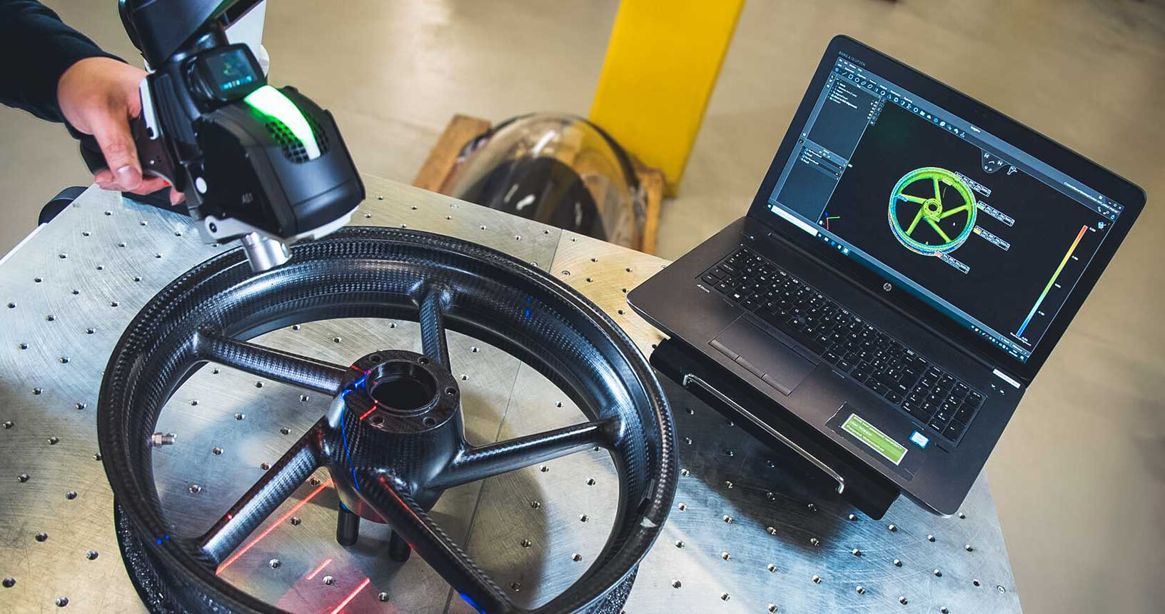 Laser scanning a carbon fibre wheel hub with the Absolute Scanner AS1 mounted on a portable measuring arm with software on laptop screen.