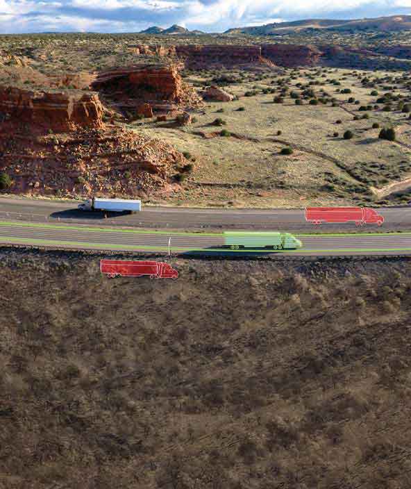 Semi-trucks drive along a highway in a desert