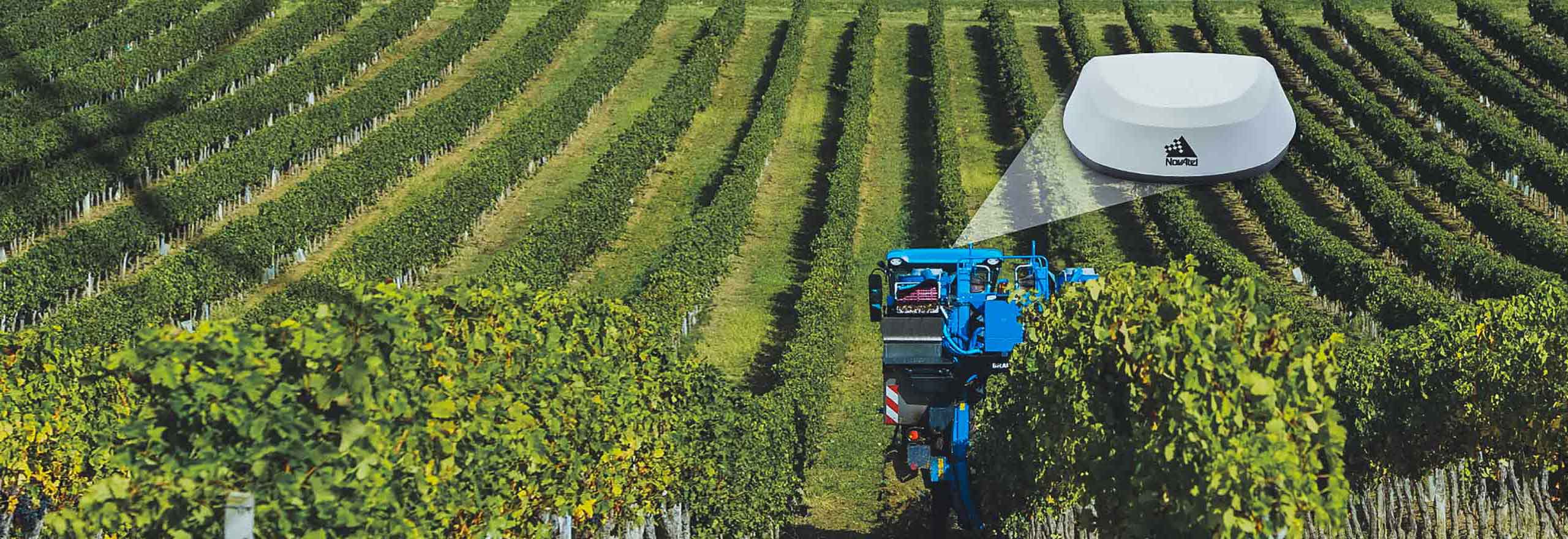Sprayer in an orchard with a GNSS SMART antenna on the roof.