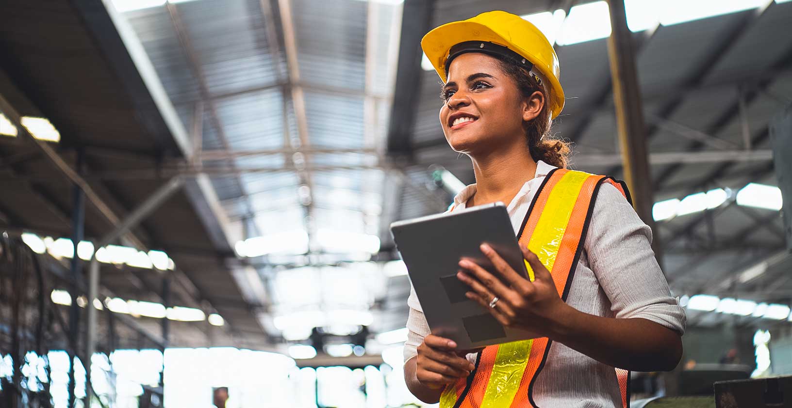 Retrato de trabalhador industrial em pé segurando um tablet e realizando a manutenção de ativos de construção