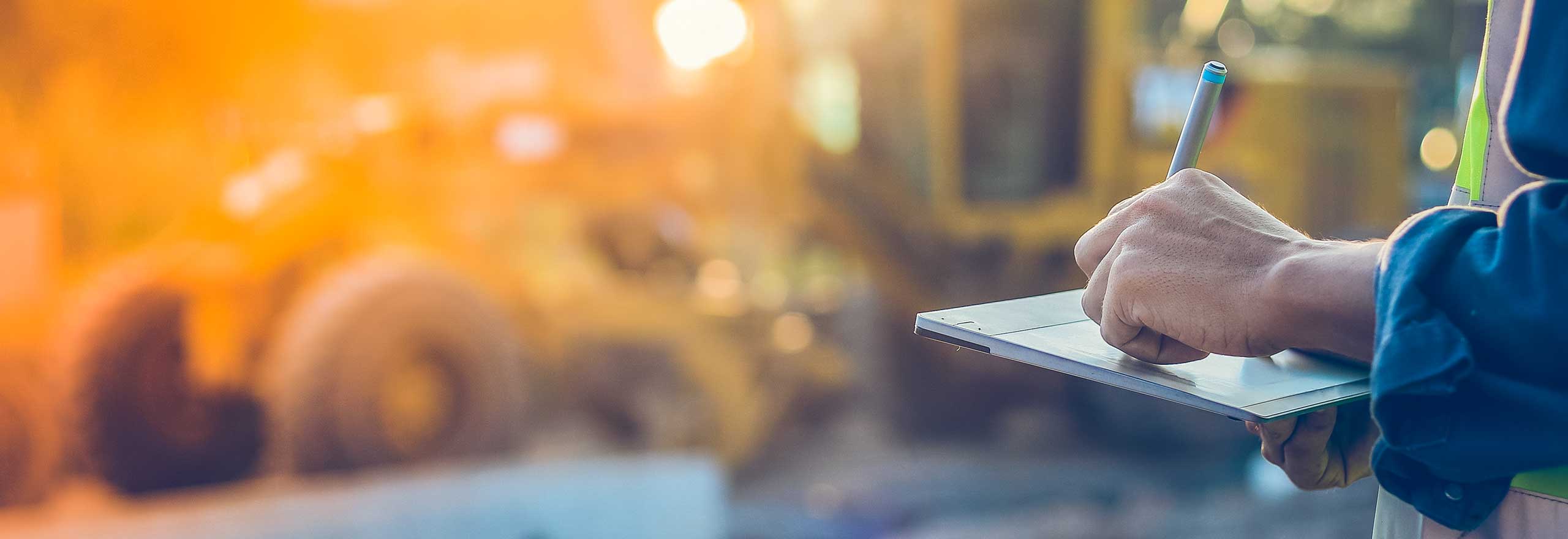 A construction worker uses a tablet and digital pin to take notes