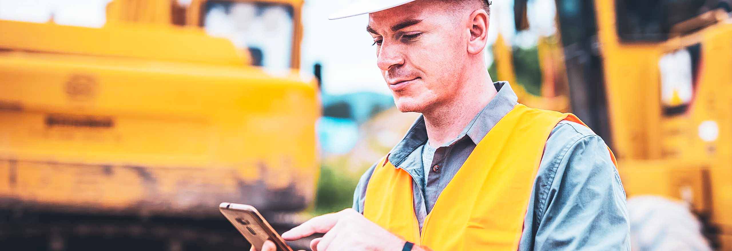 Um trabalhador da construção olhando para um celular