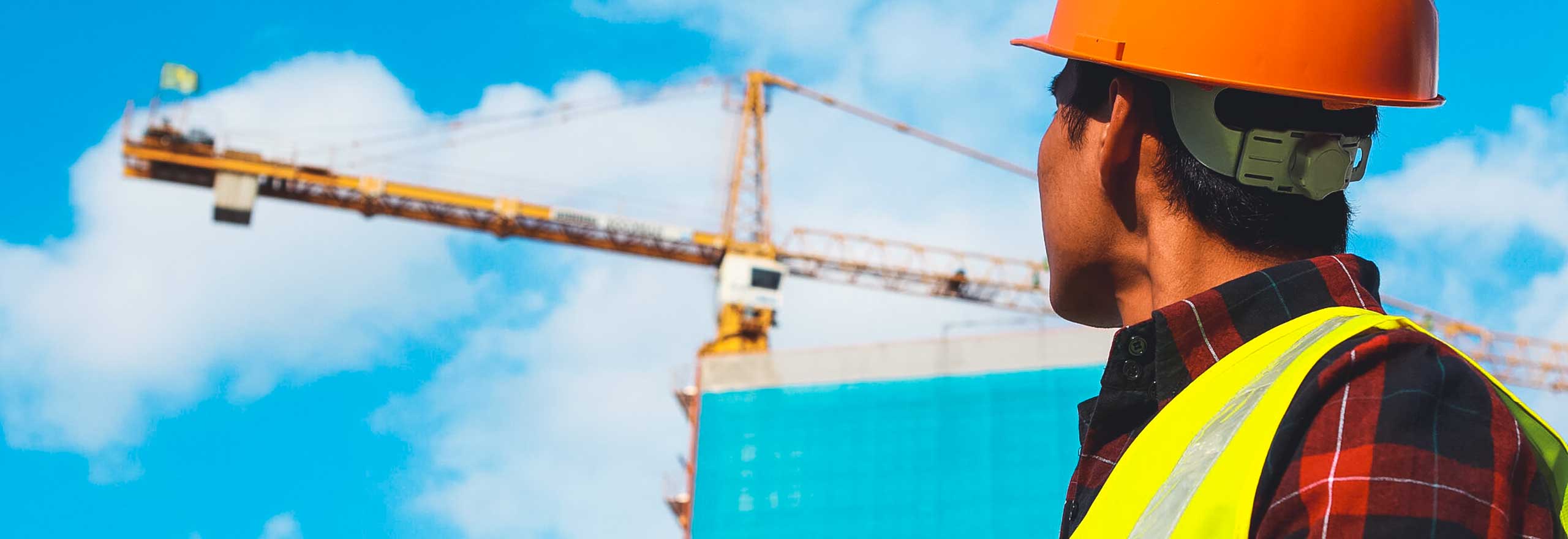 A construction worker looks toward a crane