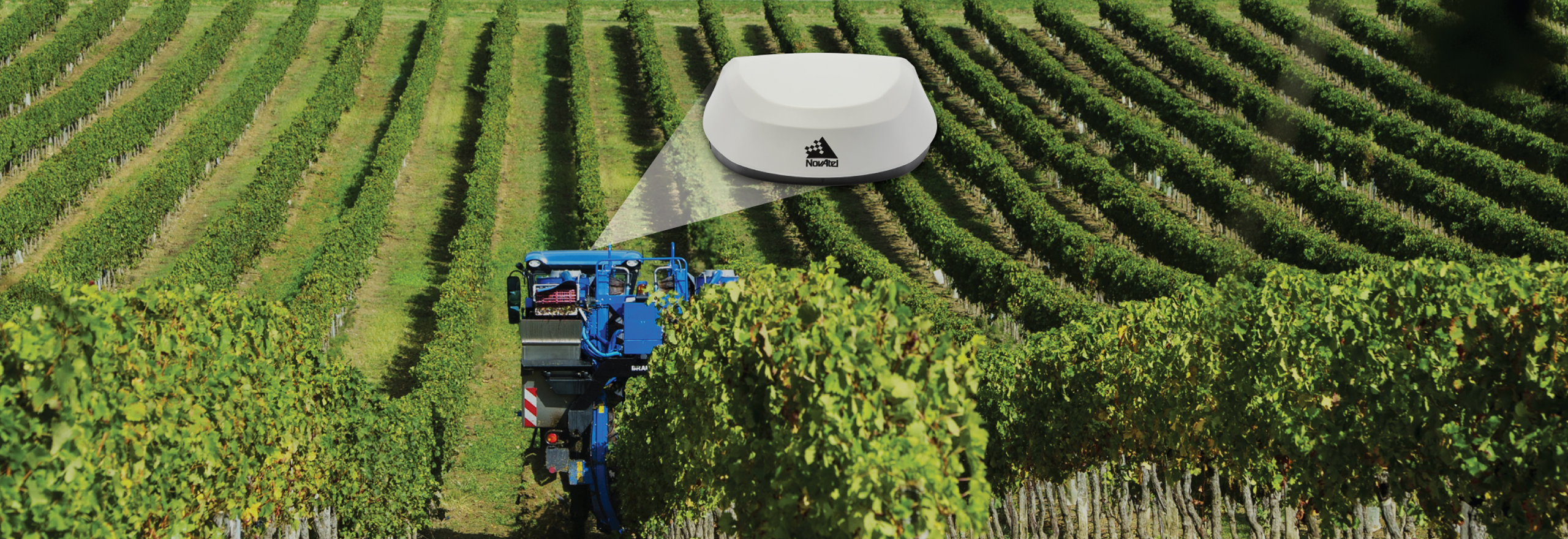 Blue vineyard equipment attending to rows of crops with a white NovAtel SMART7 Antenna shown. 