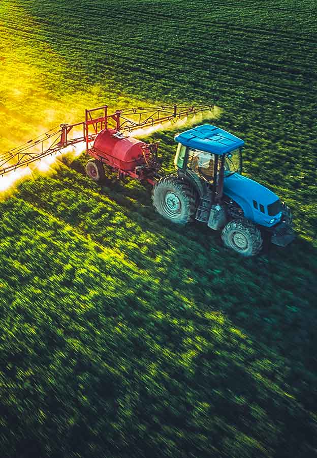 Aerial view of farming tractor plowing and spraying on field with motion blur