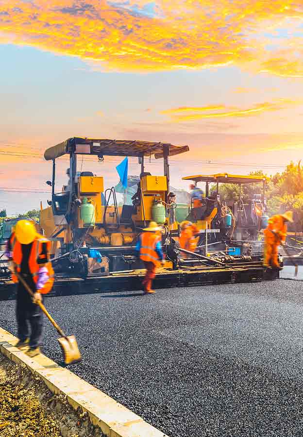 アスファルト舗装機で新しい道路を施工する建設作業員