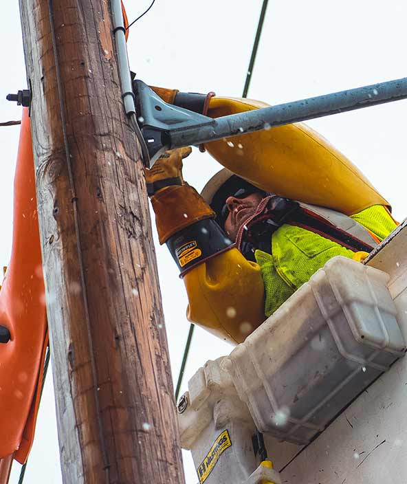 An electric company worker makes repairs on an electric pole 