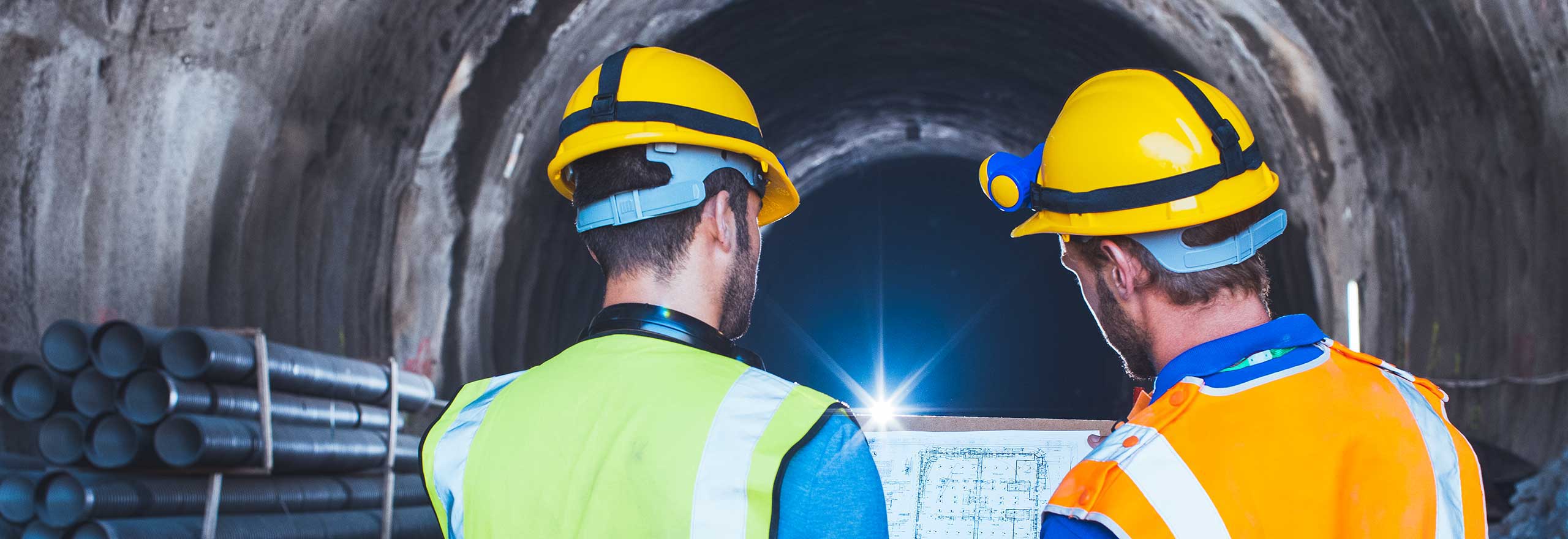 Arbeiter prüfen digitalisierte CAD-Zeichnungen in einem Tunnel