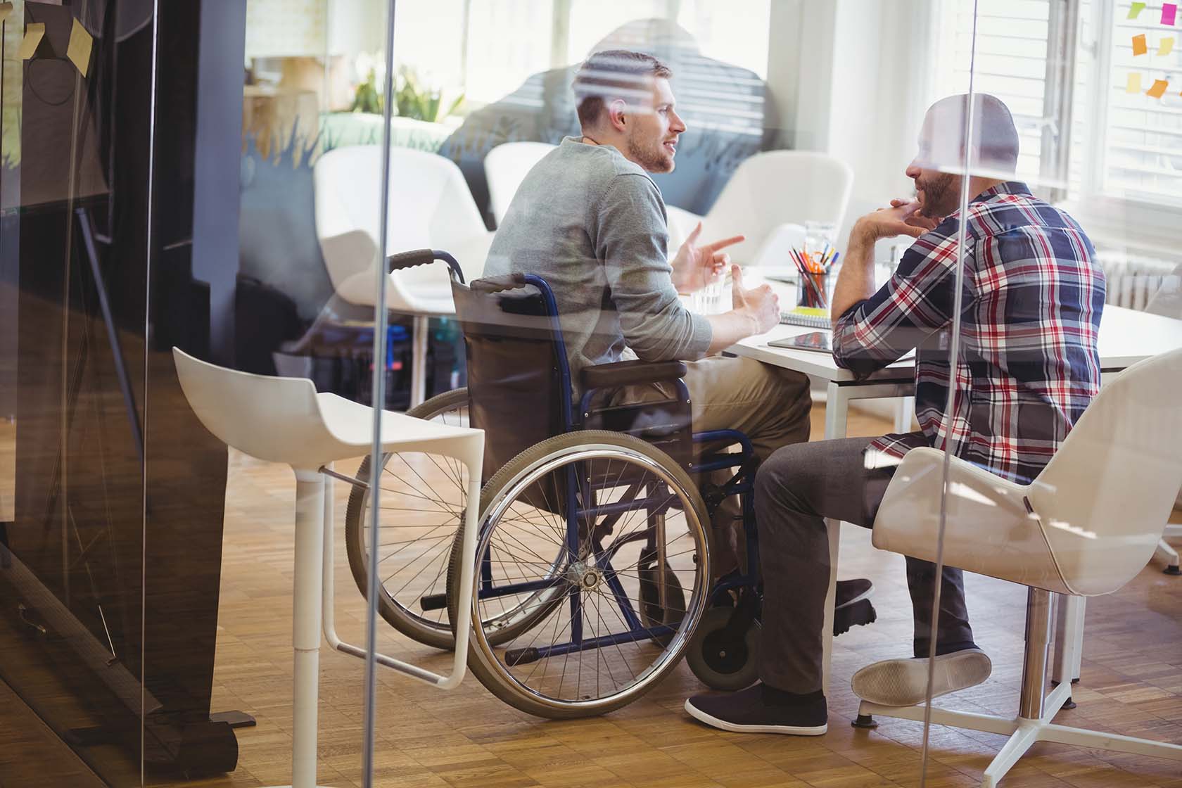 Man in a wheelchair talking to another man in a conference room