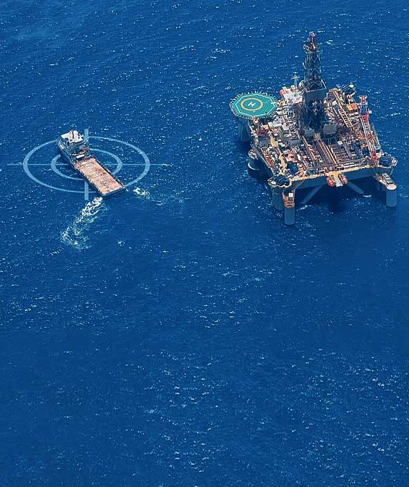 A vessel and offshore oil rig in the middle of the ocean. 