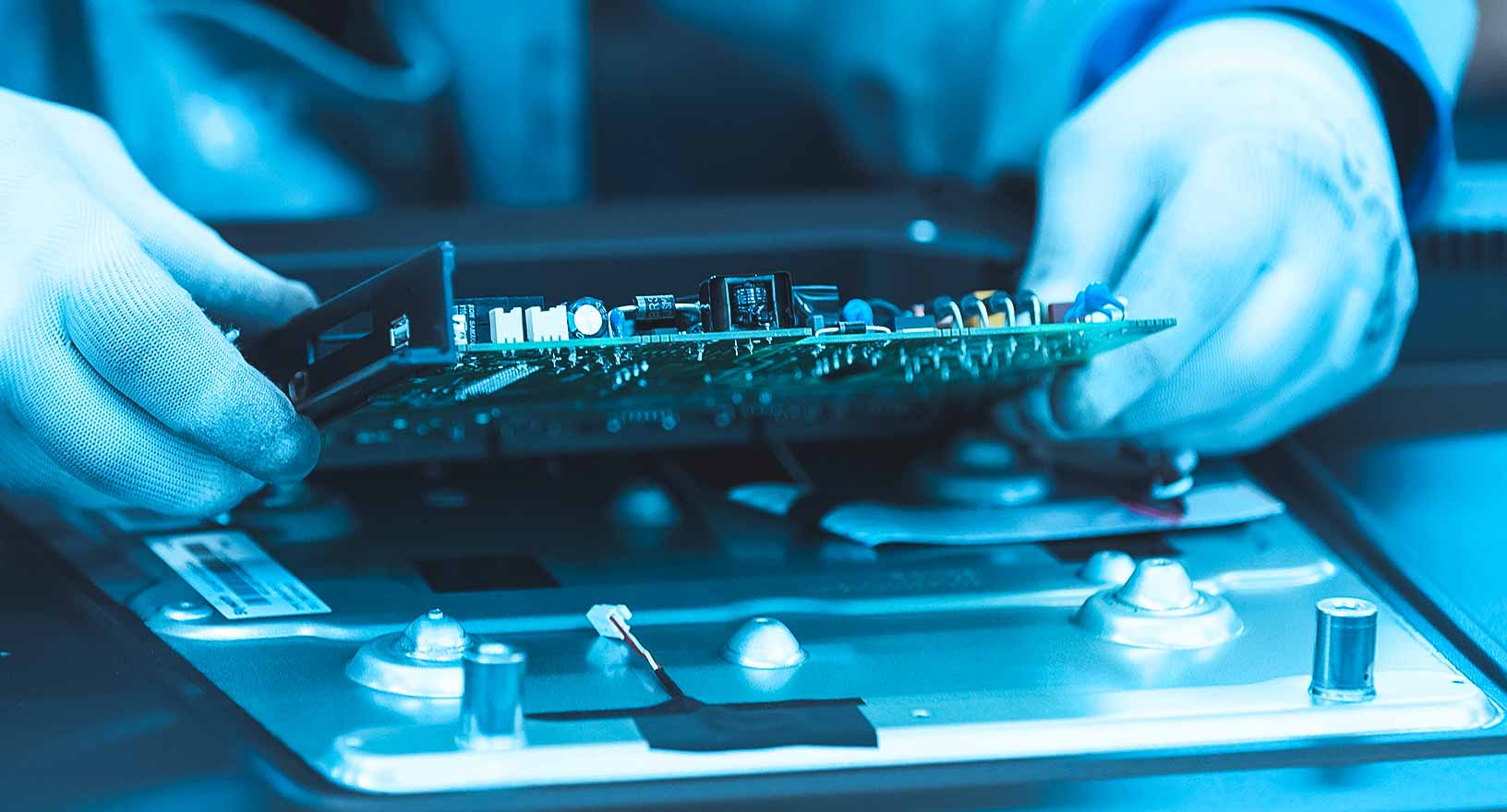 Un travailleur d’une usine de fabrication de produits de consommation inspecte un circuit imprimé. 