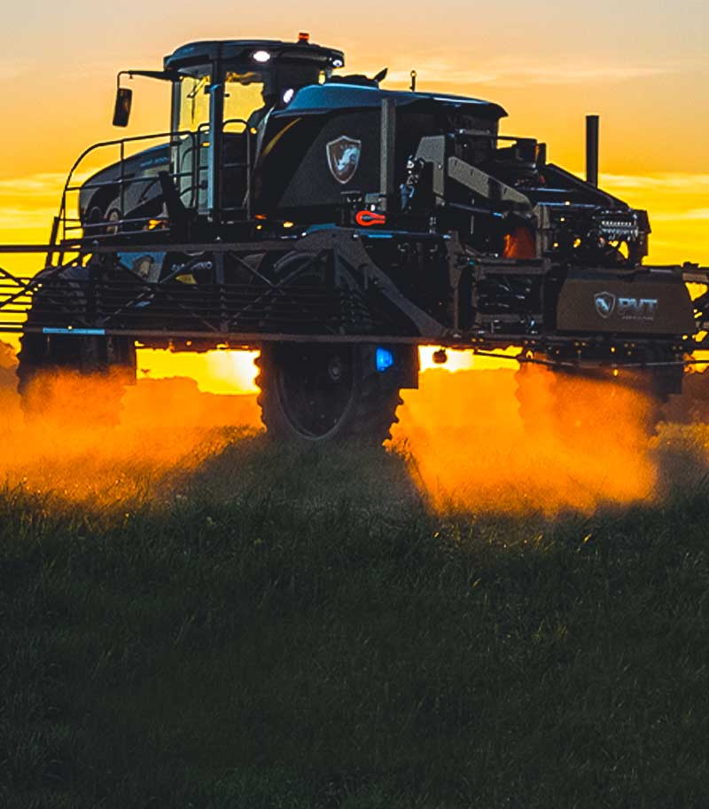 A tractor in a field at sunset