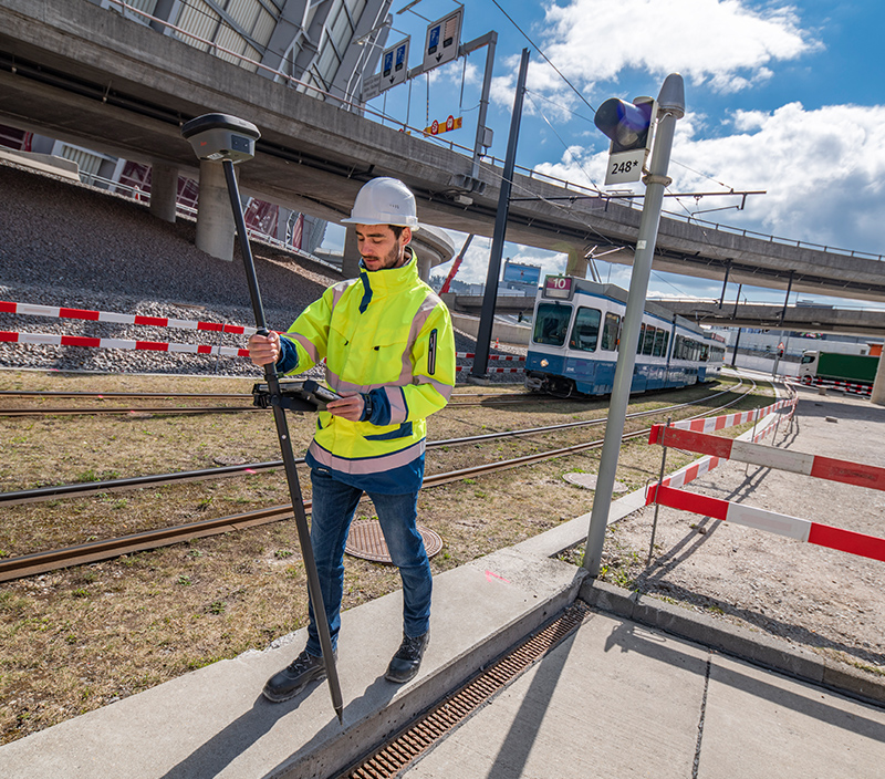 topógrafo medindo pontos em um canteiro de obras ferroviárias com uma antena inteligente