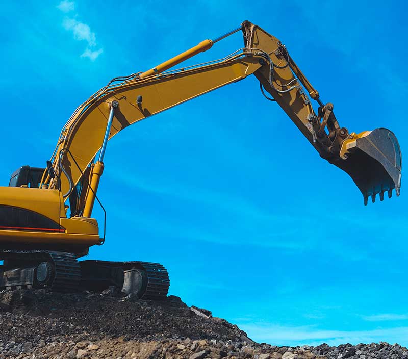 A yellow excavator atop a mound of dirt, framed by a beautiful blue sky, depicting the potential of automation construction