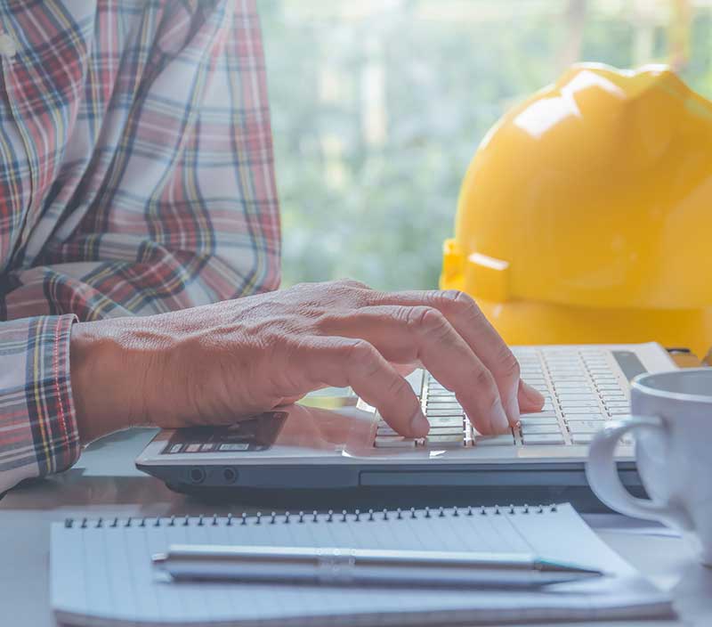 A construction executive who has returned from a successful day onsite and is viewing important metrics on his laptop enabled by automation in construction 