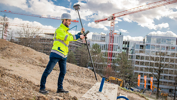 surveyor measures points on a building construction site with an RTK rover smart antenna
