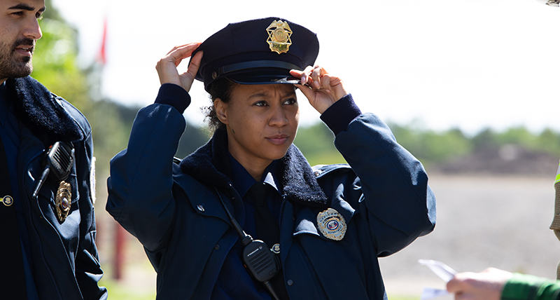 A police woman adjust her hat as she approaches a crash scene