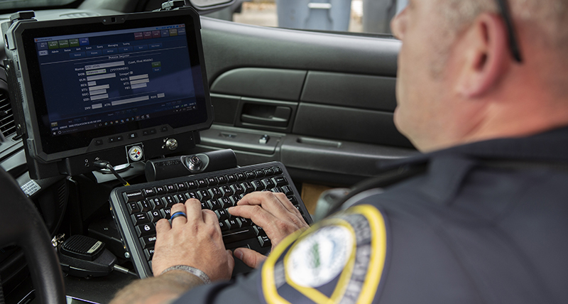 A male police officer enters data via his car computer