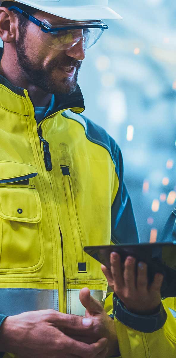 Mitarbeiter einer Industrieanlage mit Schutzhelmen und leuchtend gelben Warnwesten