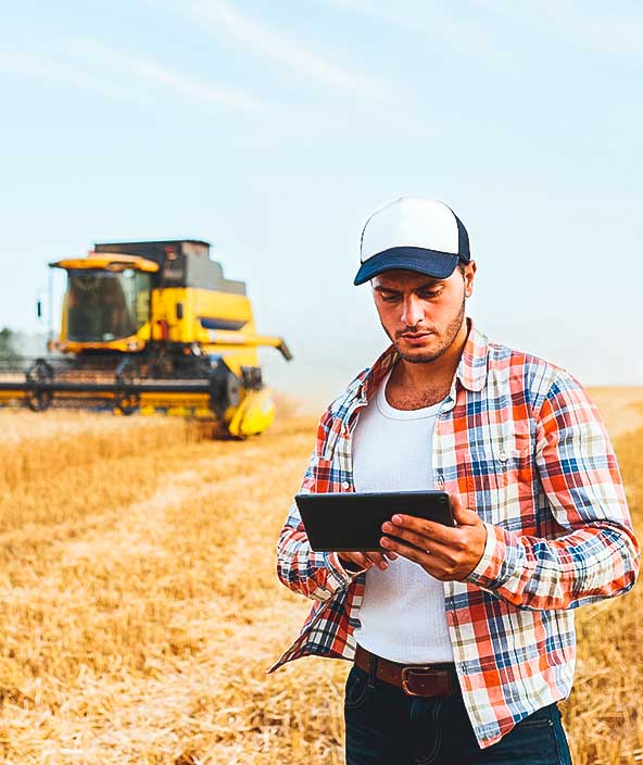 Agricultor sosteniendo tableta para guiar y controlar la cosechadora con un moderno sistema de automatización