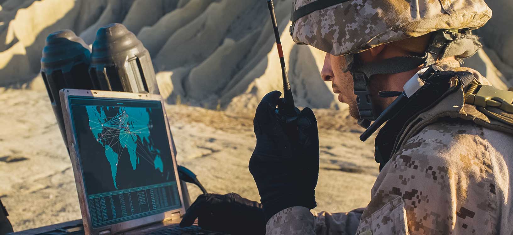 Soldaten verwenden Laptop und Funkgerät zur Kommunikation während eines Militäreinsatzes in der Wüste