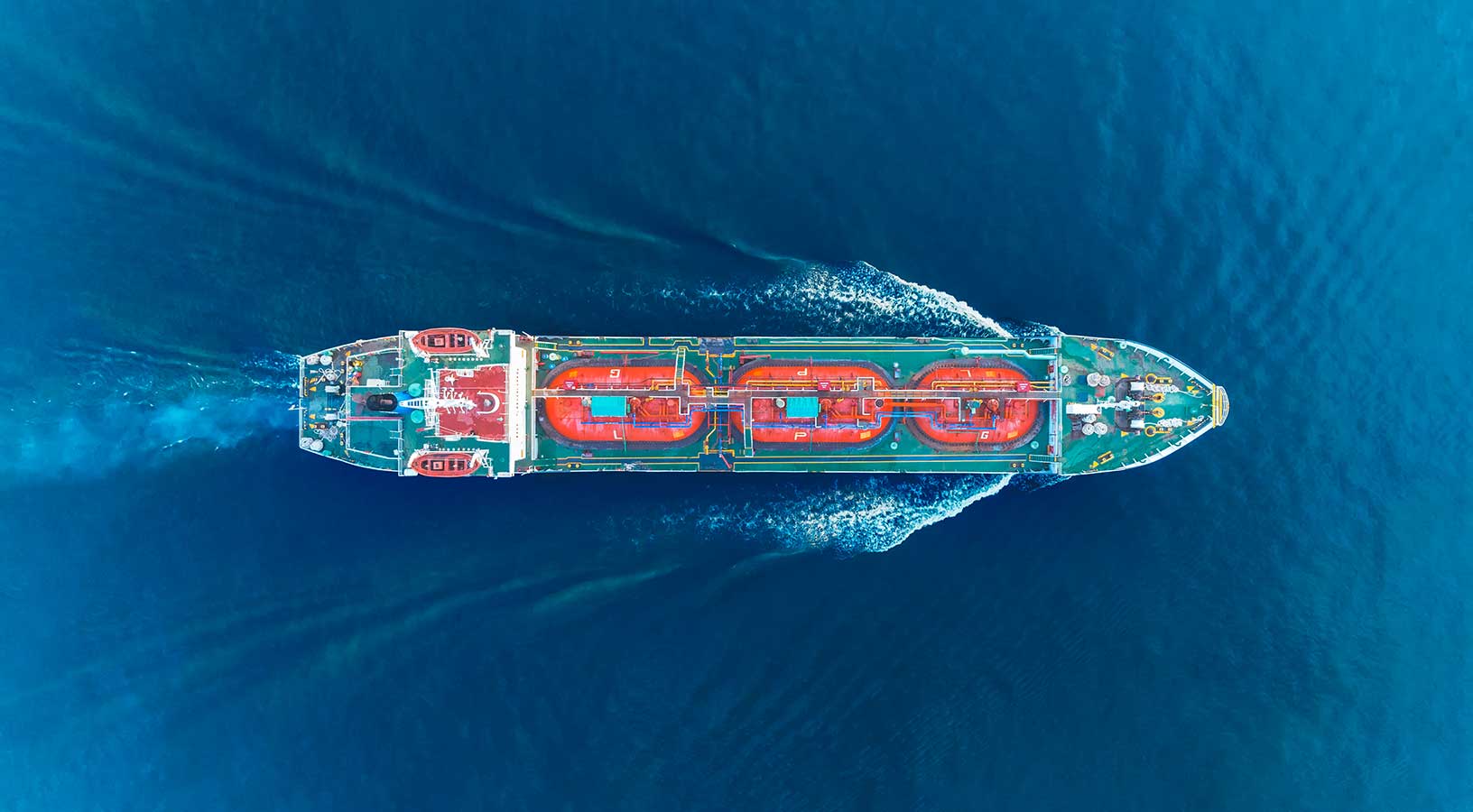 An aerial view of a dredging vessel navigating to the right of the image.