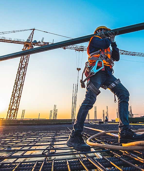 Ouvrier de construction sur un chantier avec une grue au fond.