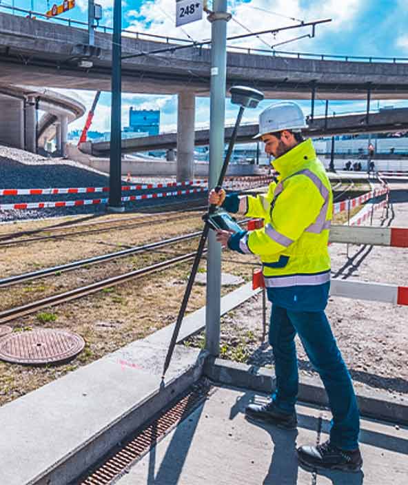 Ein Vermessungsingenieur stellt seine Ausrüstung in der Nähe einer Eisenbahnschiene auf