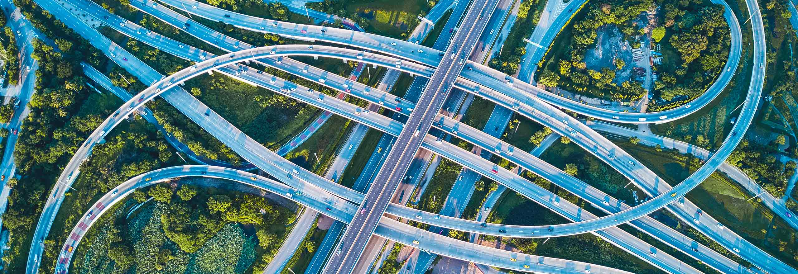 Aerial drone shot of road interchange or highway intersection with busy urban traffic speeding on the road