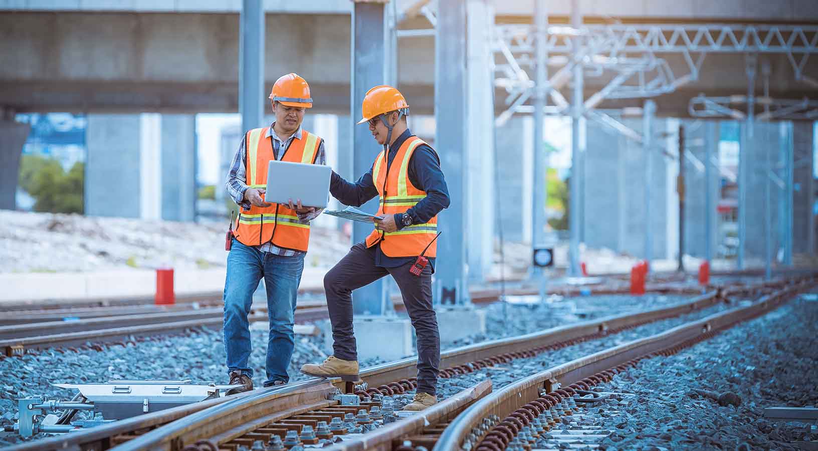 Engineer under discussion inspection and checking construction process railway switch and checking work on railroad station. Engineer wearing safety uniform and safety helmet at work.